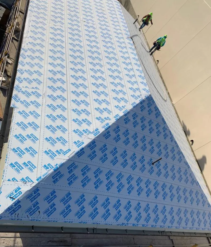 Professional roofers installing underlayment on a metal roof in Weare